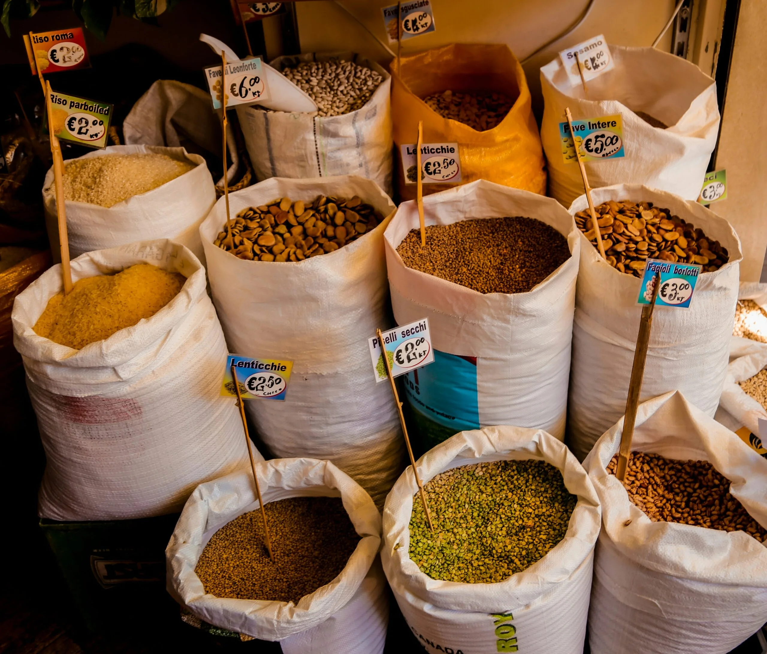 A VARIETY OF ESSENTIAL KITCHEN STAPLES, INCLUDING OLIVE OIL, SPICES, PASTA, AND CANNED TOMATOES, ON A KITCHEN COUNTERTOP.