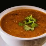 A BOWL OF HEARTY LENTIL AND VEGETABLE SOUP, GARNISHED WITH FRESH HERBS, PERFECT FOR A HEALTHY VEGETARIAN MEAL.