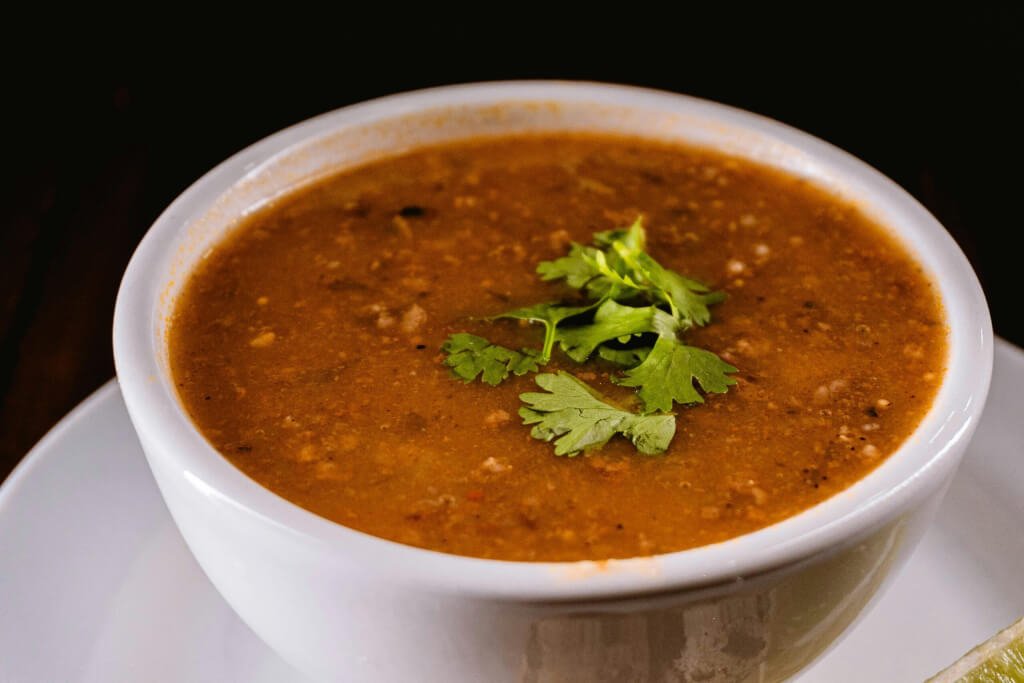 A BOWL OF HEARTY LENTIL AND VEGETABLE SOUP, GARNISHED WITH FRESH HERBS, PERFECT FOR A HEALTHY VEGETARIAN MEAL.